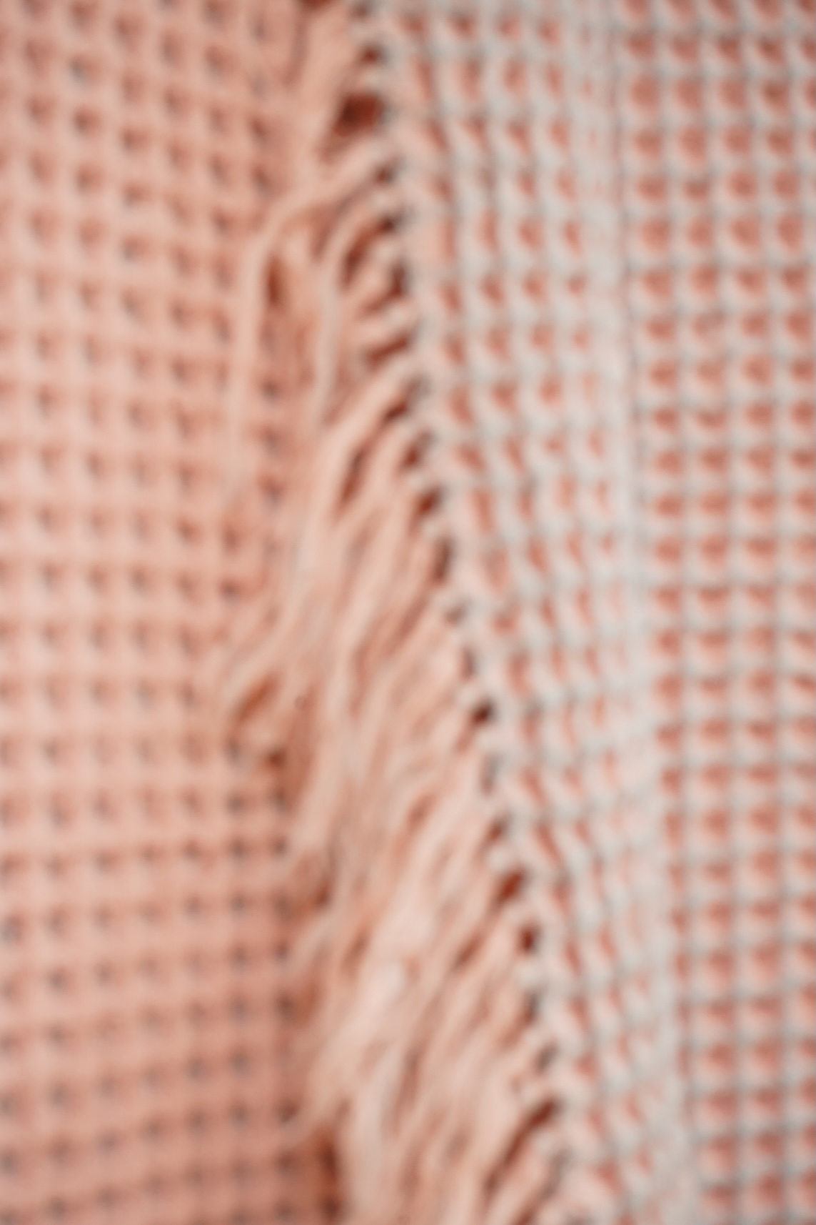 A pink and grey Welsh blanket with tasseled edges